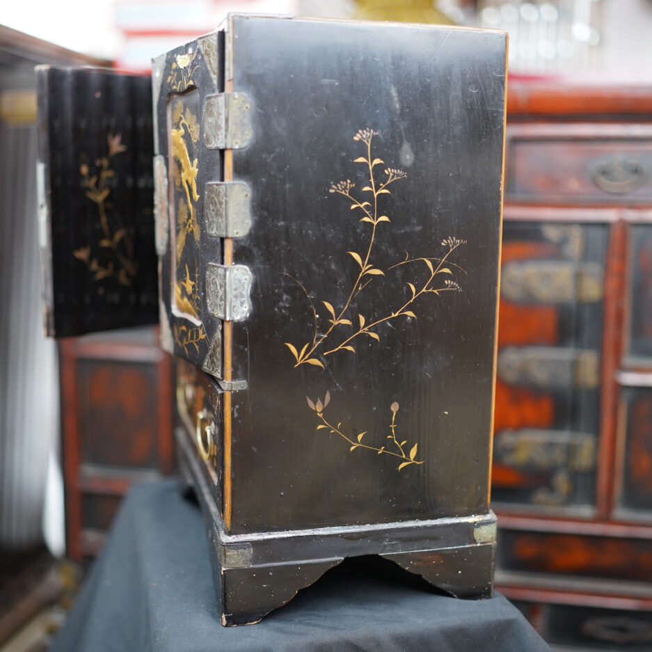 Cabinet en bois laqué noir à motifs de faucon et pins, branchages... en hira maki-e à huit tiroirs et deux portes.