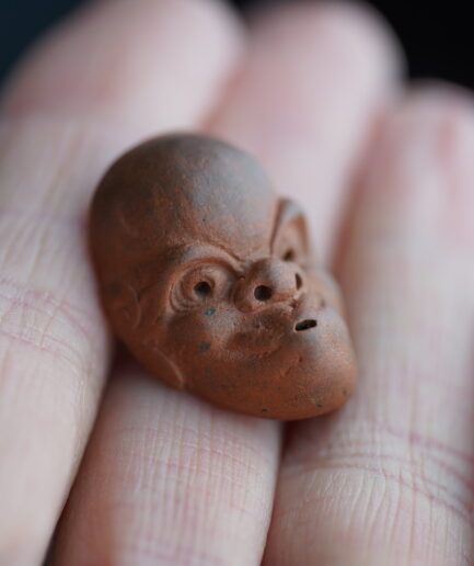 Netsuke représentant un masque Hyottoko en céramique - Début Meiji XIXe s.